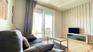 a living room with a couch and a television at The Cliffs A Ribeira - Polas in Foz