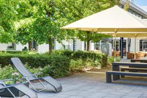 a group of chairs and a table and an umbrella at IntercityHotel Frankfurt Airport in Frankfurt/Main