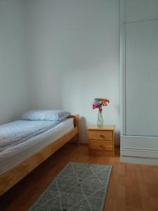 a bedroom with a bed and a vase of flowers on a table at Apartman Kulenović in Kulen Vakuf