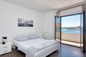 a white bedroom with a bed and a large window at Apartments by the sea Tisno, Murter - 812 in Tisno