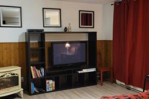 ein Wohnzimmer mit einem Fernseher auf einem Ständer in der Unterkunft Le Repaire Secret in Saint-Donat-de-Montcalm