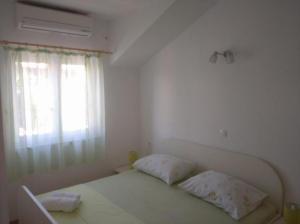 a white bedroom with a bed and a window at Apartments with parking space Bol, Brac - 12980 in Bol