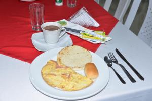 a white plate with a breakfast of omelet and a cup of coffee at Hotel El Jardín Cafetero Armenia in Armenia