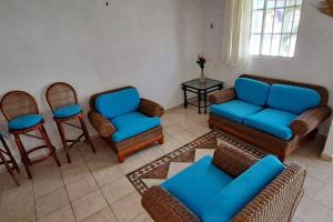 a living room with blue chairs and a table at Lugar auténtico para vacacionar in La Sabana