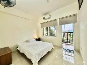 a white bedroom with a bed and a window at SARAH HOMESTAY in Thôn Lại Thê