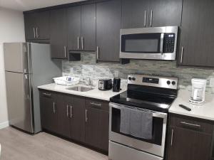 a kitchen with stainless steel appliances and wooden cabinets at PineOrange Home in Saskatoon
