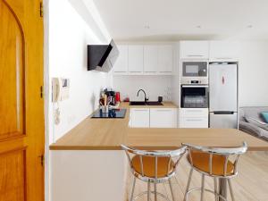 a kitchen with a counter and two bar stools at Appartement moderne 3 chambres, terrasse, proche plage et commerces - FR-1-785-12 in Mèze