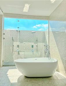 a white bath tub in a bathroom with a large window at Luxury Pool Villa 99 in Ban Bang Krang