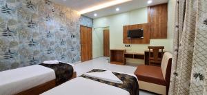 a room with two beds and a desk and a television at New Sun International & Banquet Hall in Jamshedpur