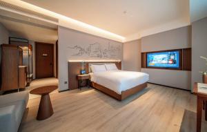 成都市にあるUrCove By HYATT Chengdu Wenshu Monasteryのベッドとテレビがあるホテルの部屋