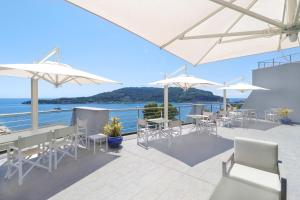 韦内雷港Cristallo Park Hotel的庭院配有白色的桌椅和遮阳伞。