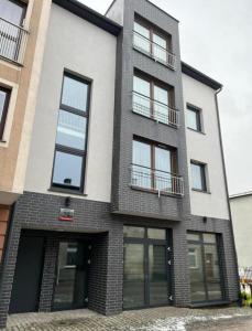 a tall brick building with windows on a street at Apartament Wałowa 4 in Wejherowo +4 photos