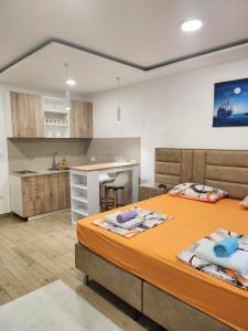 a bedroom with a large bed and a kitchen at Lena Apartman in Lastva
