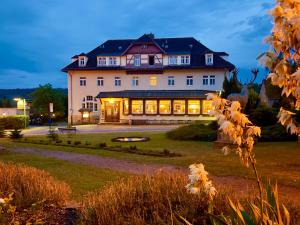 a large building with lights on in a yard at Parkhotel Forsthaus in Tharandt