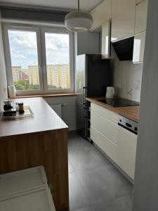 a kitchen with white cabinets and a large window at Apartament Street Art ZASPA - wśród murali in Gdańsk
