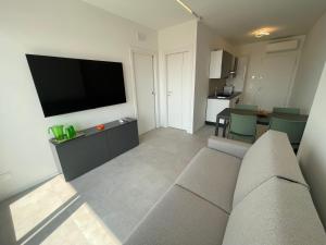 a living room with a couch and a flat screen tv at Seaview Levante new Apartments - Agenzia Cocal in Caorle