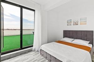 a bedroom with a bed and a large window at Azure Bliss Terrace Apartaments in Mamaia Nord