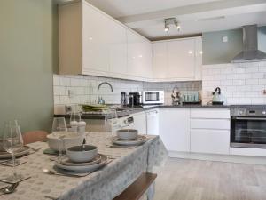 a kitchen with white cabinets and a table with dishes on it at 1 Hamilton Terrace in Lamlash