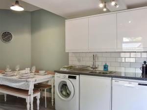 a kitchen with a washing machine and a table at 1 Hamilton Terrace in Lamlash +8 photos