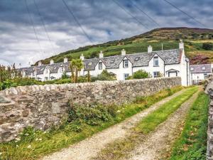a row of houses on a hill with a stone wall at The Apostles in Catacol +7 photos