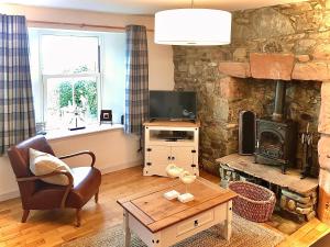 a living room with a stone wall and a wood stove at The Apostles in Catacol