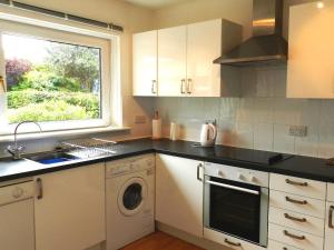 a kitchen with a washing machine and a window at Hartholm in Brodick