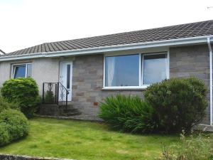 a house with a grass yard in front of it at Hartholm in Brodick