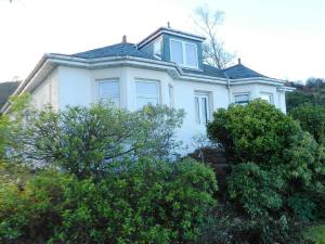 ein weißes Haus mit Bäumen davor in der Unterkunft Ardbeag in Whiting Bay