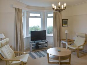 ein Wohnzimmer mit Fernseher, Stühlen und Tisch in der Unterkunft Ardbeag in Whiting Bay