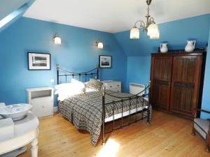 a bedroom with a bed with blue walls at Castleside Croft in Kildonan