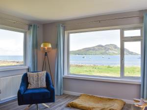 a living room with two large windows and a blue chair at Kinneil Land in Lamlash