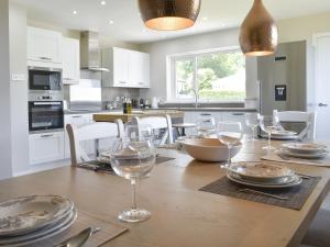 a kitchen with a wooden table with wine glasses on it at Kinneil Land in Lamlash