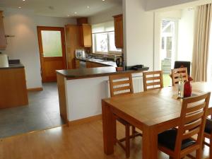 a kitchen with a wooden table and a dining room at Glen Rosa Lodge in Brodick +13 photos