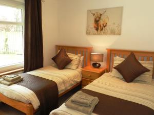 a bedroom with two beds and a picture of a bull at Glen Rosa Lodge in Brodick