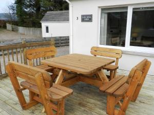 a wooden picnic table and two chairs on a deck at Glen Rosa Lodge in Brodick