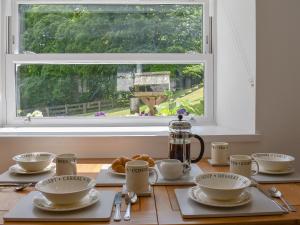 a table with cups and saucers in front of a window at Woodlea Cottage 2 in Dippin