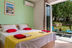 a bedroom with a bed with red pillows on it at Apartments Claudia in Šmrika