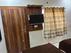 a room with a tv and a wooden cabinet at Hotel Samruddhi Residency in Jamnagar