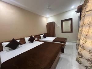 a hotel room with two beds and a mirror at Hotel Samruddhi Residency in Jamnagar