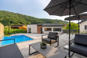 a patio with two chairs and an umbrella and a pool at Apartments & Room Forest in Slunj
