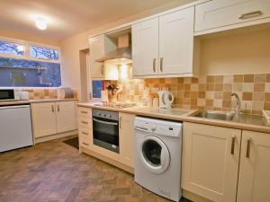 a kitchen with white cabinets and a washing machine at The Old Reading Room in Bamburgh