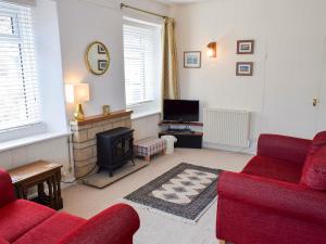 a living room with a red couch and a fireplace at The Old Reading Room in Bamburgh
