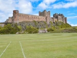 a castle on top of a hill with a field at The Old Reading Room in Bamburgh