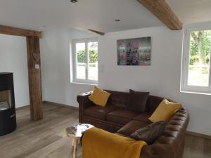 a living room with a brown couch and two windows at Gite Le dorm'eure du Val - SPA in Saint-Pierre-du-Val
