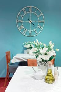 a large clock on the wall above a table with flowers at Hotel Gold in Poznań +74 photos
