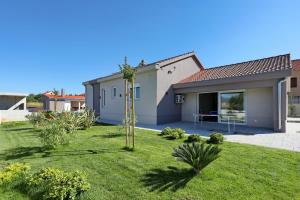 a house with a garden in front of it at Holiday home Fjaka with swimming pool in Pridraga
