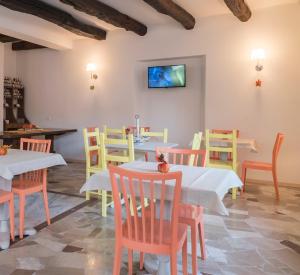 ein Esszimmer mit Tischen und Stühlen und einem TV an der Wand in der Unterkunft Chery Bed & Breakfast in Riva San Vitale