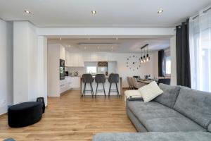 a living room with a gray couch and a kitchen at Holiday home Fjaka with swimming pool in Pridraga