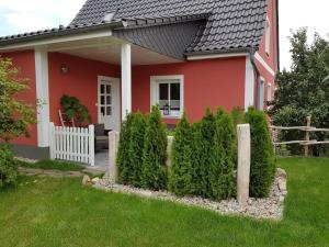 a red house with a white fence in front of it at NEU! Ferienwohnung Witaj in Panschwitz-Kuckau