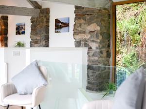 a room with a stone wall and a white chair at Awel Deg in Arthog